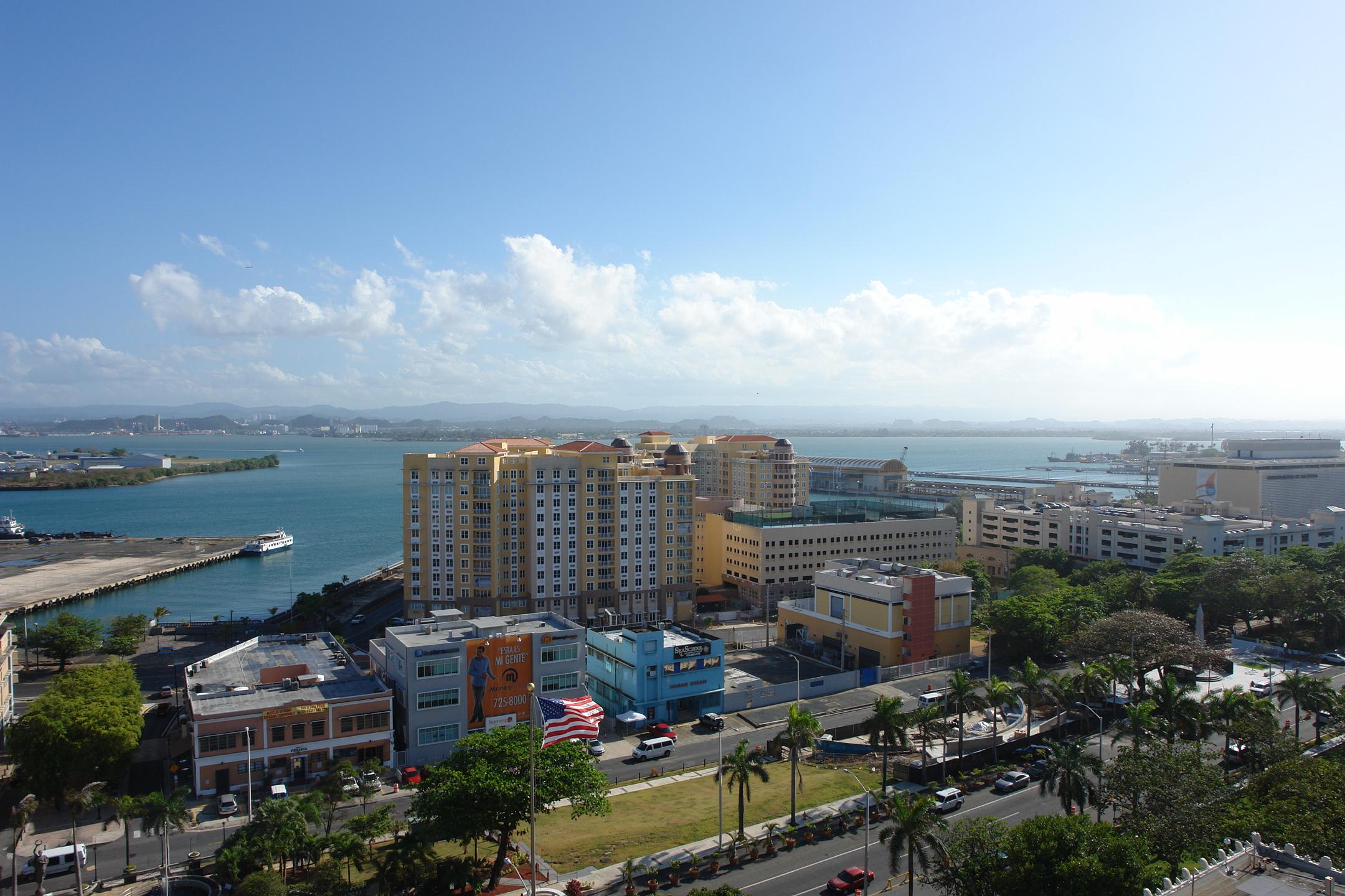 Edificios históricos; Historic buildings; Capitolios; capitols (legislative buildings); neoclásico; neoclassical; cresterías; crestings; calles; streets; automóviles; automobiles; ventanas; windows; azoteas; rooftops; Estacionamiento; parking (area); océanos; oceans (marine bodies of water); Palmas (planta); palm trees; 